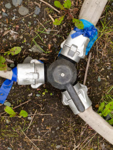 3-way diverter valve with fire hoses attached to fittings on forest floor.